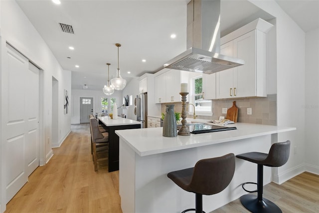791 44th Ave N, Saint Petersburg, FL 33703 - kitchen with island range hood, freestanding refrigerator, light wood-style flooring, light countertops, and backsplash