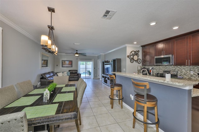 6512 Trent Creek Dr, Sun City Center, FL 33573 - kitchen featuring stainless steel appliances, crown molding, light tile patterned flooring, open floor plan, and tasteful backsplash