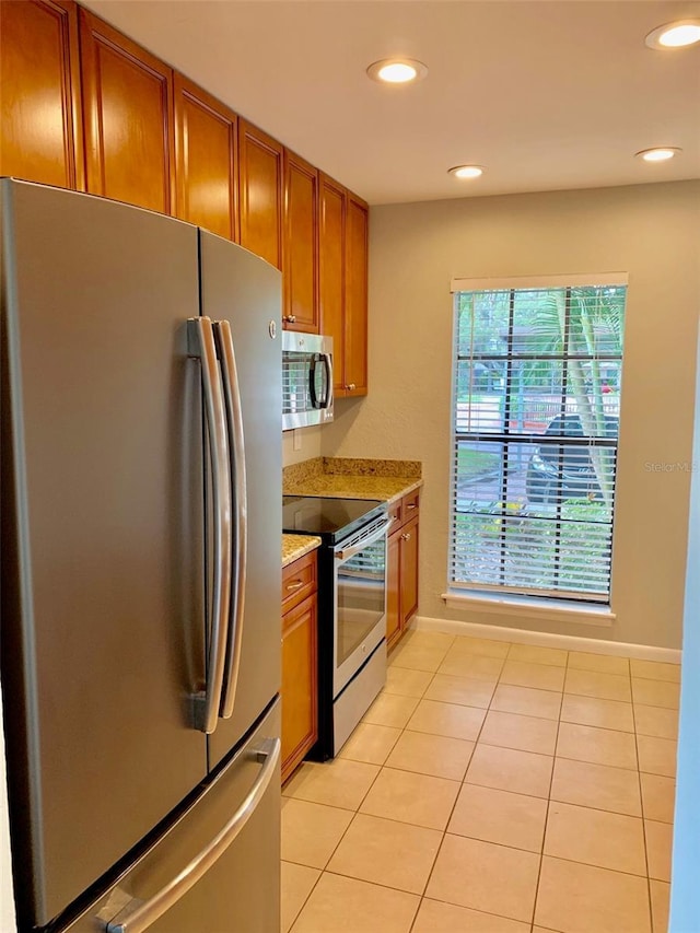 1515 Bayshore Blvd Unit 38, Dunedin, FL 34698 - kitchen featuring stainless steel appliances, brown cabinetry, light tile patterned floors, recessed lighting, and light stone counters