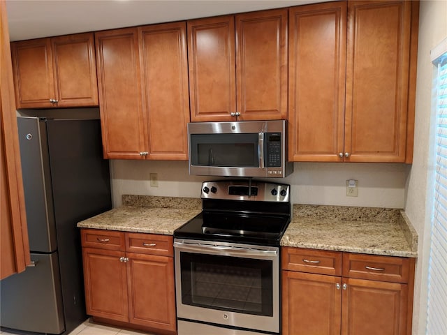 1515 Bayshore Blvd Unit 38, Dunedin, FL 34698 - kitchen with stainless steel appliances, light stone counters, and brown cabinetry