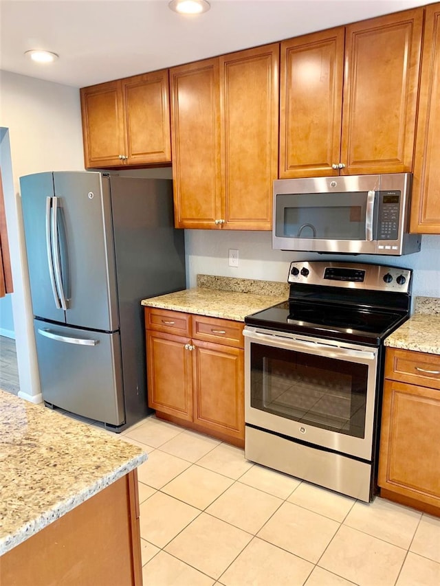 1515 Bayshore Blvd Unit 38, Dunedin, FL 34698 - kitchen featuring appliances with stainless steel finishes, light tile patterned floors, brown cabinetry, light stone counters, and recessed lighting