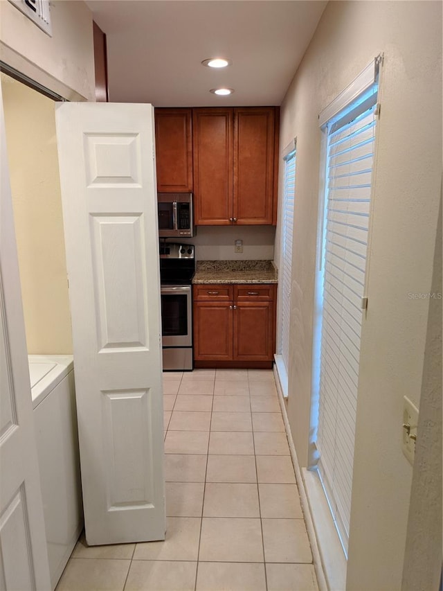 1515 Bayshore Blvd Unit 38, Dunedin, FL 34698 - kitchen featuring appliances with stainless steel finishes, light tile patterned floors, brown cabinets, recessed lighting, and light stone counters