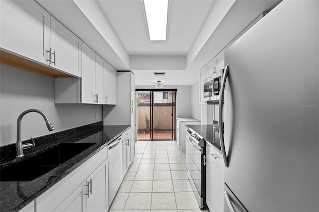 4160 Player Cir Unit 109, Orlando, FL 32808 - kitchen featuring stainless steel appliances, a sink, white cabinetry, light tile patterned flooring, and dark stone counters
