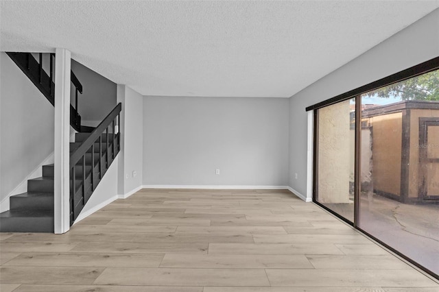 4160 Player Cir Unit 109, Orlando, FL 32808 - empty room with light wood finished floors, stairs, a textured ceiling, and baseboards