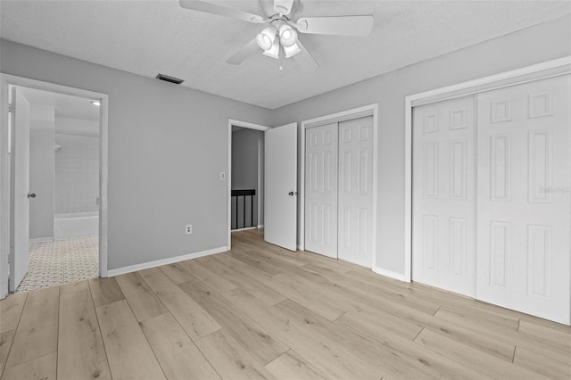 4160 Player Cir Unit 109, Orlando, FL 32808 - unfurnished bedroom featuring multiple closets, light wood-type flooring, ensuite bathroom, and a textured ceiling