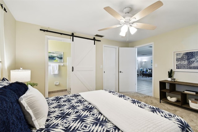 5825 Oakhurst Dr, Seminole, FL 33772 - bedroom with a barn door, light colored carpet, ensuite bath, and a ceiling fan