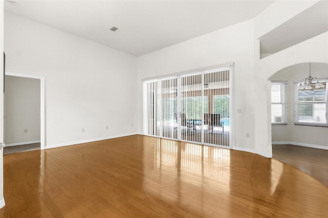 8518 N Linwood Loop, Citrus Springs, FL 34433 - spare room featuring wood finished floors, a towering ceiling, plenty of natural light, arched walkways, and baseboards