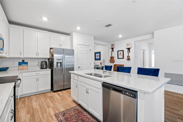 5511 Badini Way, Palmetto, FL 34221 - kitchen with stainless steel appliances, a sink, light wood-type flooring, a kitchen island with sink, and white cabinets