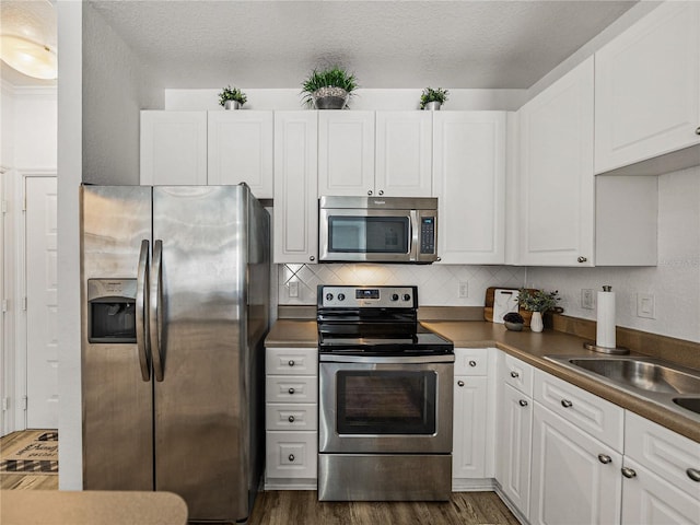 4221 W Spruce St Unit 2302, Tampa, FL 33607 - kitchen featuring appliances with stainless steel finishes, white cabinetry, dark wood finished floors, and backsplash