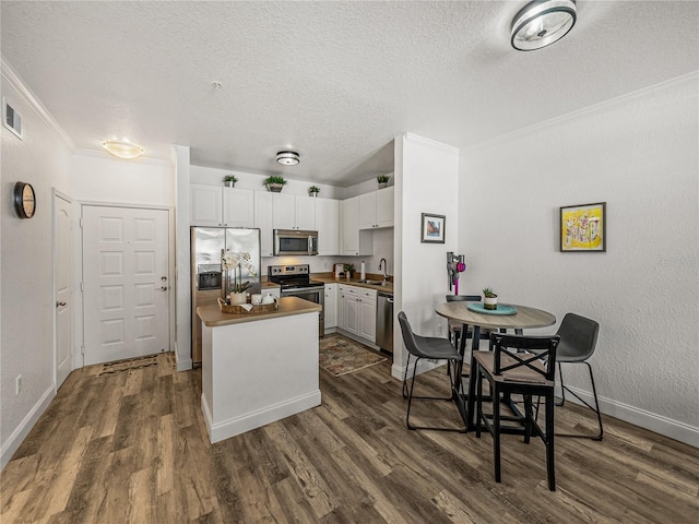 4221 W Spruce St Unit 2302, Tampa, FL 33607 - kitchen featuring stainless steel appliances, a sink, a textured ceiling, ornamental molding, and dark wood-style flooring
