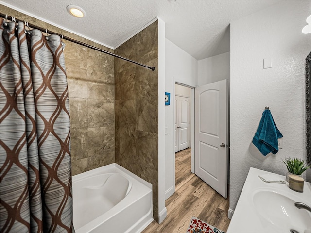 4221 W Spruce St Unit 2302, Tampa, FL 33607 - full bathroom with a textured ceiling, wood finished floors, shower / tub combo, a sink, and baseboards