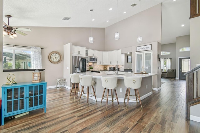 12102 Steppingstone Blvd, Tampa, FL 33635 - kitchen with appliances with stainless steel finishes, high vaulted ceiling, ceiling fan, white cabinets, and a breakfast bar area