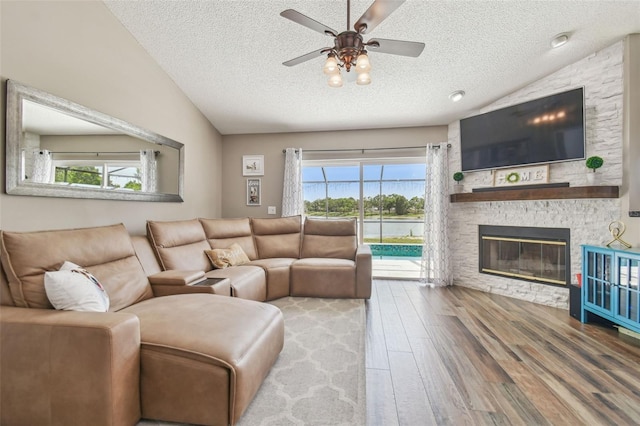 12102 Steppingstone Blvd, Tampa, FL 33635 - living room with vaulted ceiling, wood finished floors, a textured ceiling, a ceiling fan, and a stone fireplace