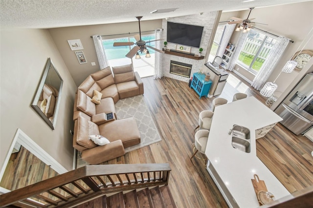 12102 Steppingstone Blvd, Tampa, FL 33635 - living area with ceiling fan, a textured ceiling, a stone fireplace, and wood finished floors