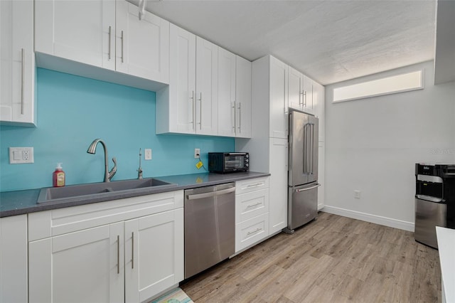 3114 Lake Pine Way Unit G1, Tarpon Springs, FL 34688 - kitchen with stainless steel appliances, a sink, light wood-type flooring, white cabinetry, and dark countertops