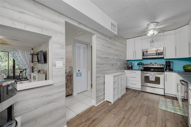 3114 Lake Pine Way Unit G1, Tarpon Springs, FL 34688 - kitchen with appliances with stainless steel finishes, ceiling fan, white cabinetry, light wood-style flooring, and wood walls