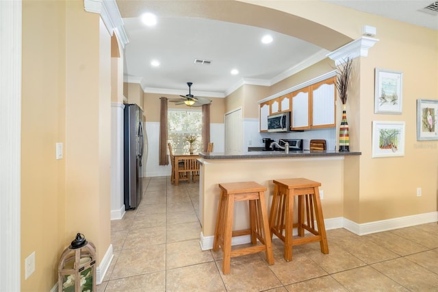 11813 Crawford Parrish Ln, Parrish, FL 34219 - kitchen with stainless steel appliances, a peninsula, dark countertops, light tile patterned flooring, and ornamental molding