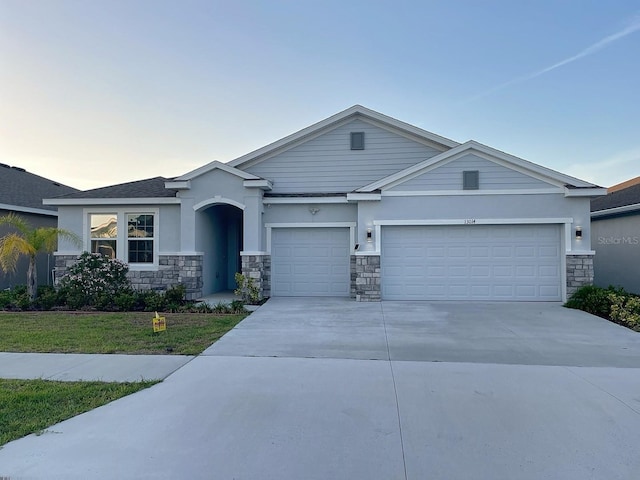 13014 Willow Grove Dr, Riverview, FL 33579 - view of front of home with a garage, stone siding, concrete driveway, and stucco siding