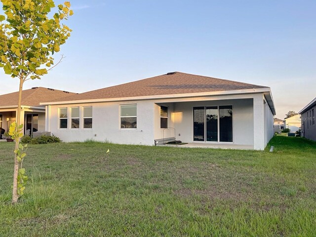 13014 Willow Grove Dr, Riverview, FL 33579 - back of property with stucco siding, a yard, and roof with shingles