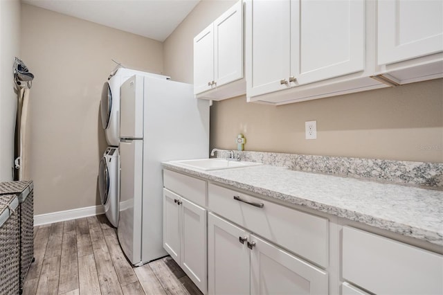 5 Sweetgum Ct N, Homosassa, FL 34446 - kitchen featuring stacked washer / dryer, light wood finished floors, white cabinetry, a sink, and baseboards