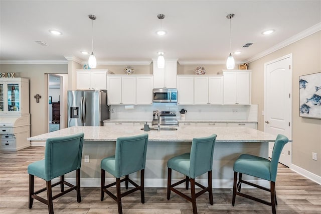 5 Sweetgum Ct N, Homosassa, FL 34446 - kitchen featuring stainless steel appliances, white cabinetry, decorative backsplash, a center island with sink, and ornamental molding