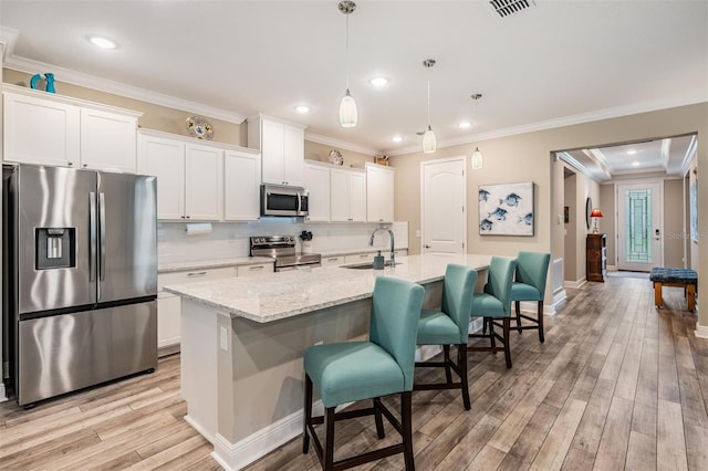 5 Sweetgum Ct N, Homosassa, FL 34446 - kitchen featuring stainless steel appliances, a kitchen island with sink, white cabinetry, decorative backsplash, and light wood-type flooring