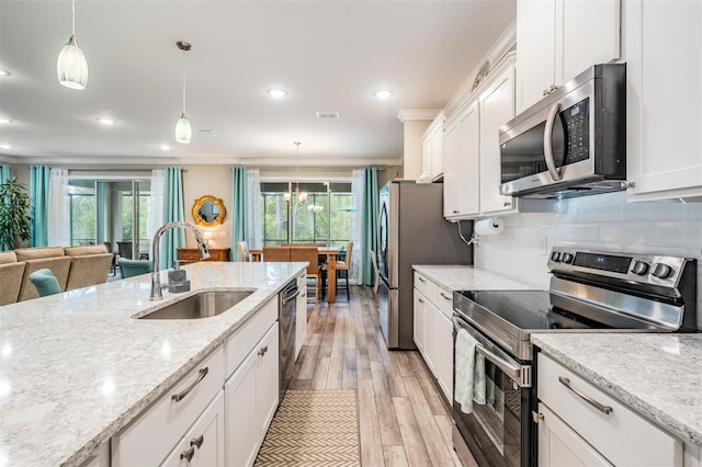 5 Sweetgum Ct N, Homosassa, FL 34446 - kitchen featuring stainless steel appliances, a sink, white cabinetry, light wood-type flooring, and decorative light fixtures