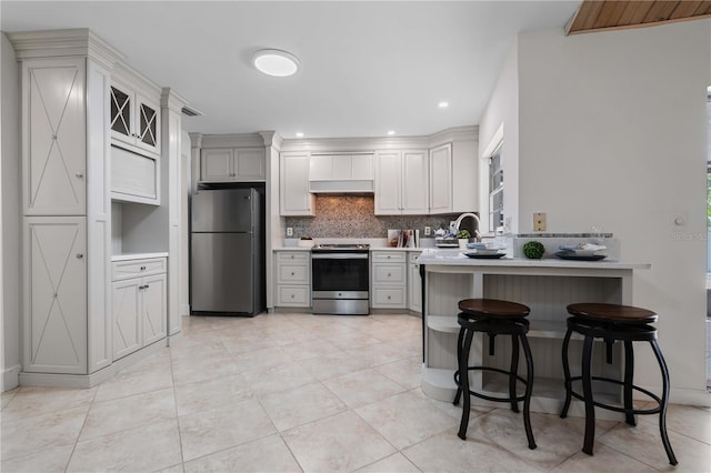 4706 Fox Hunt Dr, Tampa, FL 33624 - kitchen featuring stainless steel appliances, a peninsula, decorative backsplash, light countertops, and a kitchen breakfast bar