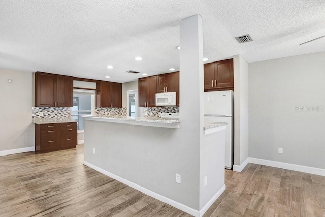 3917 Casaba Loop, Valrico, FL 33596 - kitchen featuring white appliances, light wood-type flooring, decorative backsplash, recessed lighting, and a textured ceiling