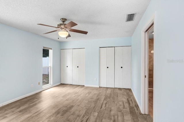 3917 Casaba Loop, Valrico, FL 33596 - unfurnished bedroom with two closets, wood finished floors, a textured ceiling, baseboards, and ceiling fan