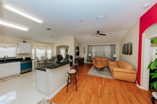 9852 Laurel Ledge Dr, Riverview, FL 33569 - kitchen with dishwasher, vaulted ceiling, dark countertops, a breakfast bar, and white cabinetry