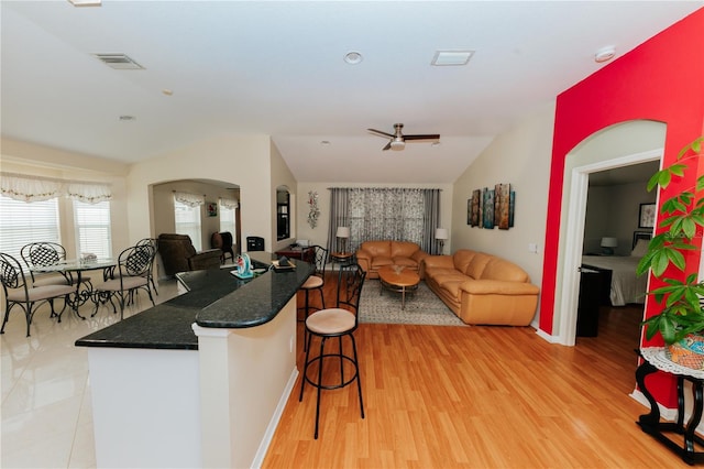 9852 Laurel Ledge Dr, Riverview, FL 33569 - kitchen featuring vaulted ceiling, open floor plan, a breakfast bar, ceiling fan, and light wood-style floors