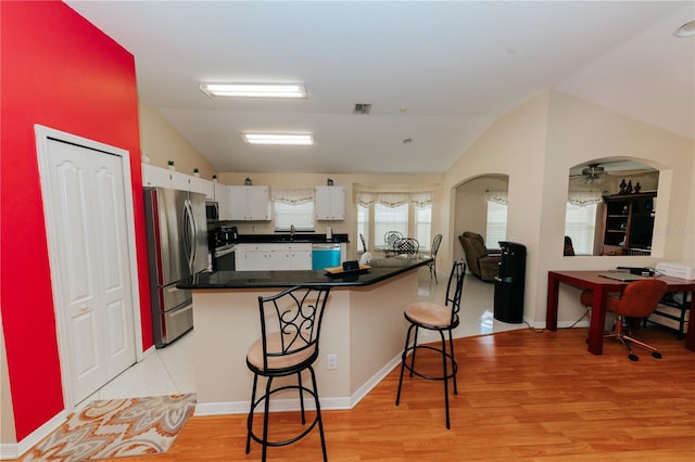 9852 Laurel Ledge Dr, Riverview, FL 33569 - kitchen featuring appliances with stainless steel finishes, dark countertops, white cabinetry, lofted ceiling, and a breakfast bar