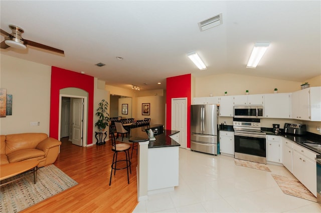 9852 Laurel Ledge Dr, Riverview, FL 33569 - kitchen featuring stainless steel appliances, dark countertops, vaulted ceiling, white cabinets, and ceiling fan