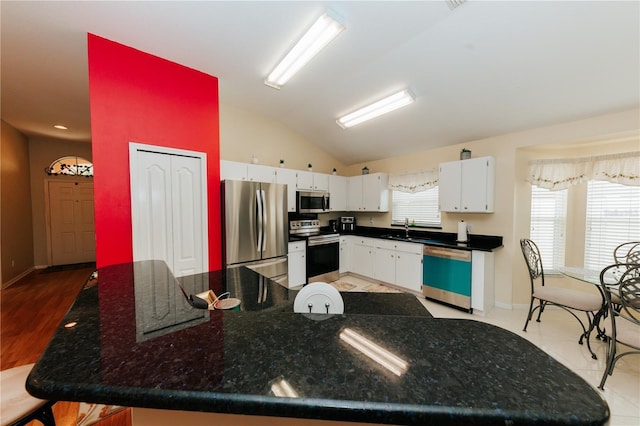 9852 Laurel Ledge Dr, Riverview, FL 33569 - kitchen with stainless steel appliances, vaulted ceiling, white cabinets, and dark stone counters