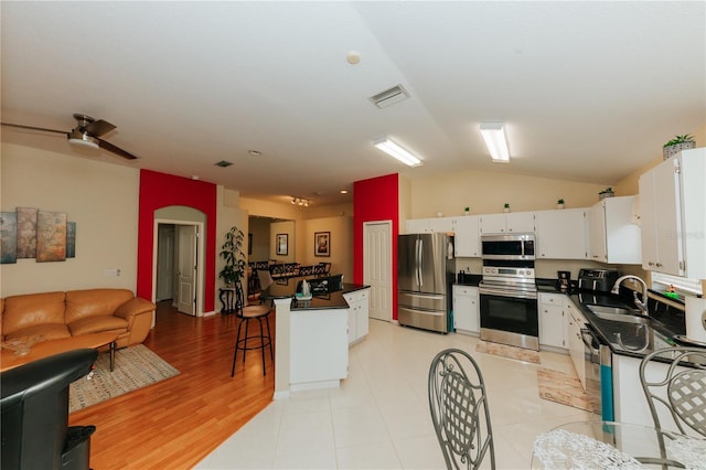 9852 Laurel Ledge Dr, Riverview, FL 33569 - kitchen featuring stainless steel appliances, dark countertops, open floor plan, lofted ceiling, and white cabinets