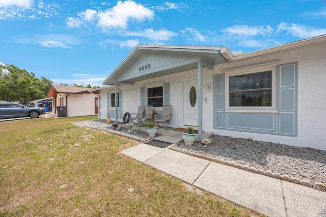 6639 Winding Oak Dr, Tampa, FL 33625 - ranch-style house with a porch, a front yard, and stucco siding