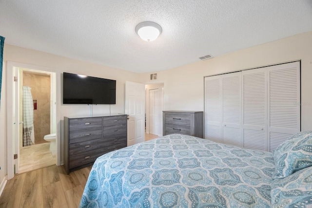 6639 Winding Oak Dr, Tampa, FL 33625 - bedroom featuring wood finished floors, a textured ceiling, a closet, and ensuite bath