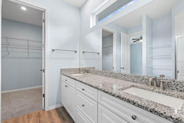 11016 Kiskadee Cir, New Port Richey, FL 34654 - bathroom with a spacious closet, double vanity, baseboards, a ceiling fan, and wood finished floors