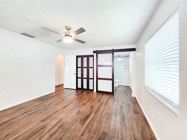 4102 Stonehenge Rd, Mulberry, FL 33860 - empty room with a barn door, ceiling fan, wood finished floors, a textured ceiling, and baseboards