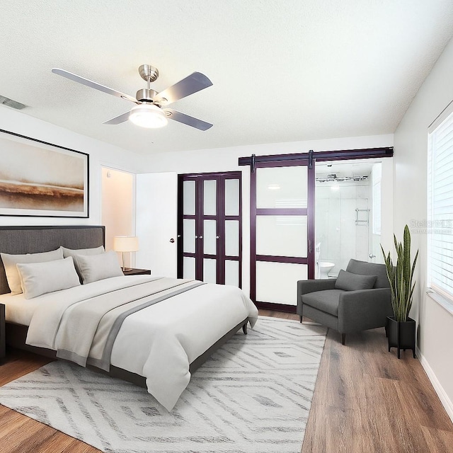 4102 Stonehenge Rd, Mulberry, FL 33860 - bedroom featuring wood finished floors, a barn door, and a ceiling fan