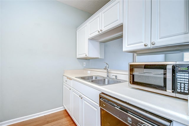 800 S Dakota Ave Unit 429, Tampa, FL 33606 - kitchen featuring dishwasher, a sink, light wood-style floors, baseboards, and white cabinets