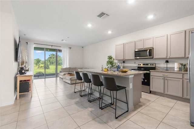 34248 Redwood Dawn Ln, Wesley Chapel, FL 33543 - kitchen featuring stainless steel appliances, a kitchen bar, open floor plan, gray cabinetry, and recessed lighting