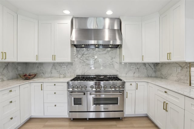 1709 Main St, Safety Harbor, FL 34695 - kitchen with wall chimney exhaust hood, stainless steel range, white cabinetry, backsplash, and recessed lighting