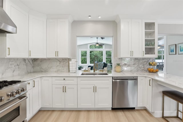 1709 Main St, Safety Harbor, FL 34695 - kitchen with appliances with stainless steel finishes, a sink, wall chimney exhaust hood, white cabinetry, and light wood-type flooring