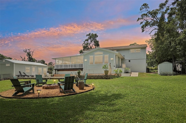 1709 Main St, Safety Harbor, FL 34695 - back of house at dusk featuring an outdoor fire pit, a sunroom, and a yard