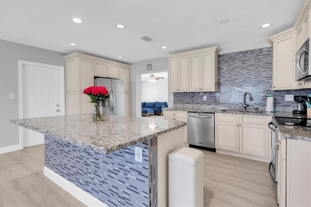 5685 35th Ave N, Saint Petersburg, FL 33710 - kitchen featuring appliances with stainless steel finishes, a sink, cream cabinets, light wood finished floors, and recessed lighting