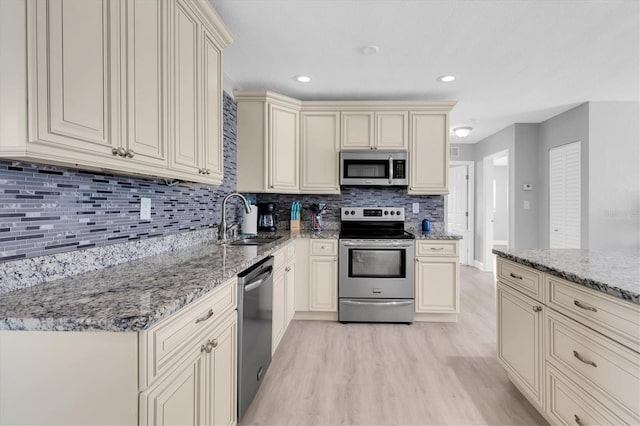 5685 35th Ave N, Saint Petersburg, FL 33710 - kitchen with stainless steel appliances, cream cabinets, a sink, light wood finished floors, and tasteful backsplash