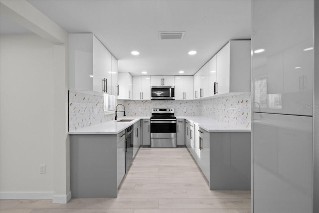 15025 Shark St, Hudson, FL 34667 - kitchen featuring appliances with stainless steel finishes, a sink, light wood-style flooring, backsplash, and recessed lighting