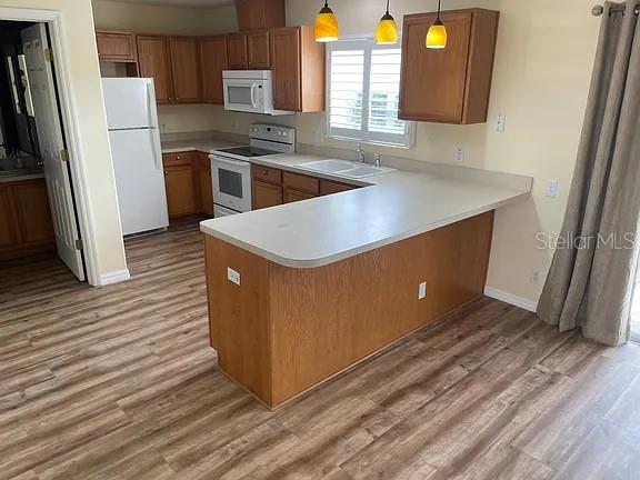 13290 Thoroughbred Loop, Largo, FL 33773 - kitchen featuring white appliances, light wood-style flooring, brown cabinetry, and light countertops